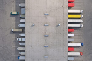 Aerial view of goods warehouse. Logistics center in industrial city zone from above. Aerial view of trucks loading at logistic center