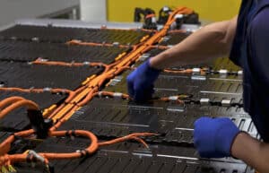 Close-up of a technician's hands assembling a lithium battery for electric cars on the production line of an electric car factory.