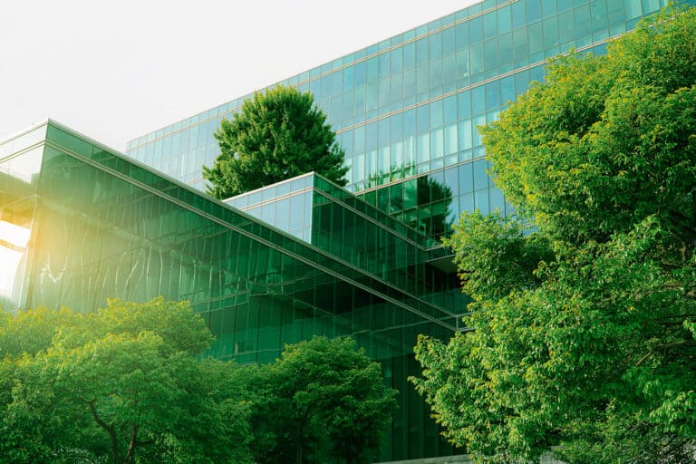 Glass office building surrounded by green trees.