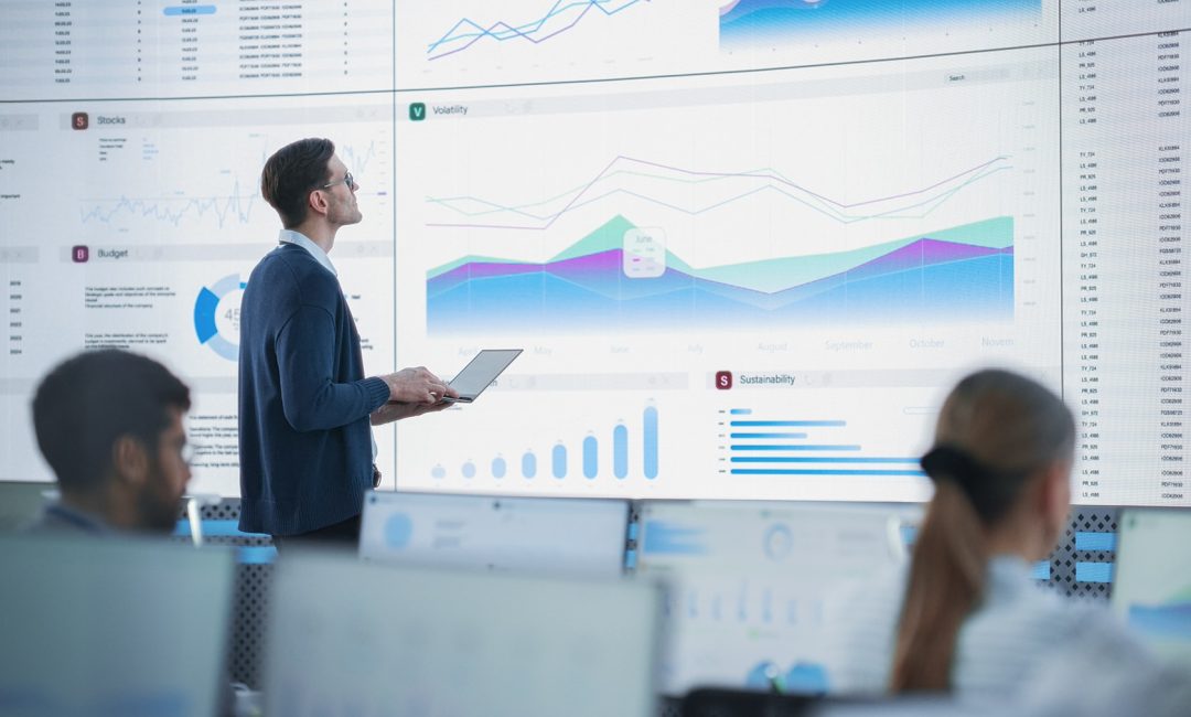 Data Analyst Reviewing Financial Information And Reports on Big Digital Screen